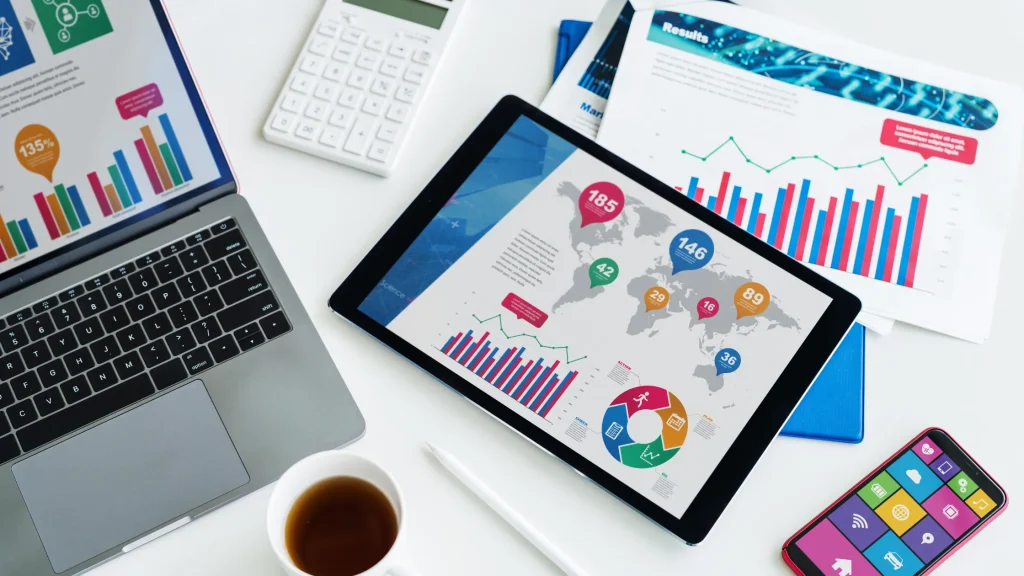 A laptop, tablet, and smartphone showing digital marketing analysis with graphs and charts for market research.