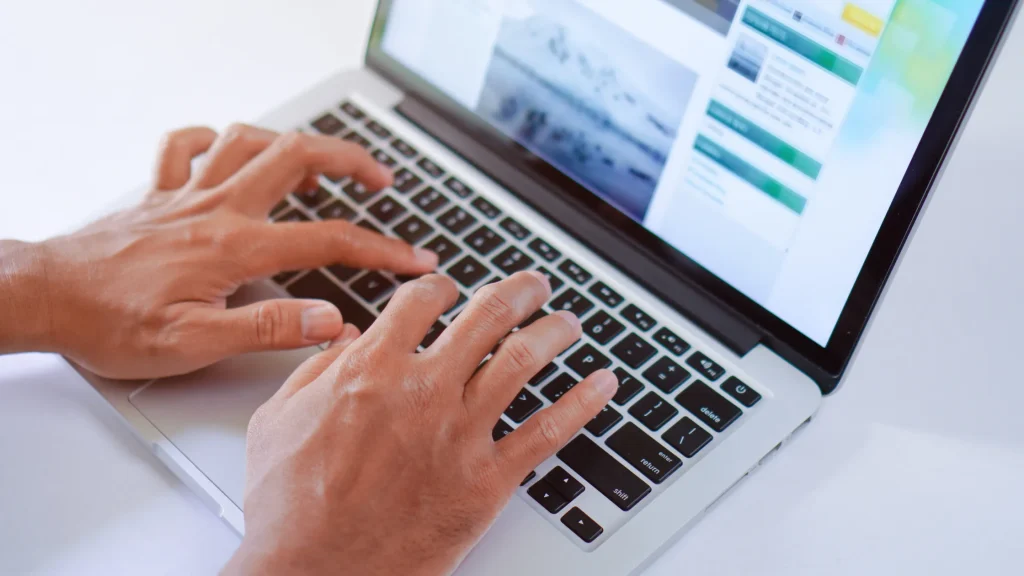 Person typing on a laptop while researching, using SEO content writing services UK to enhance content.